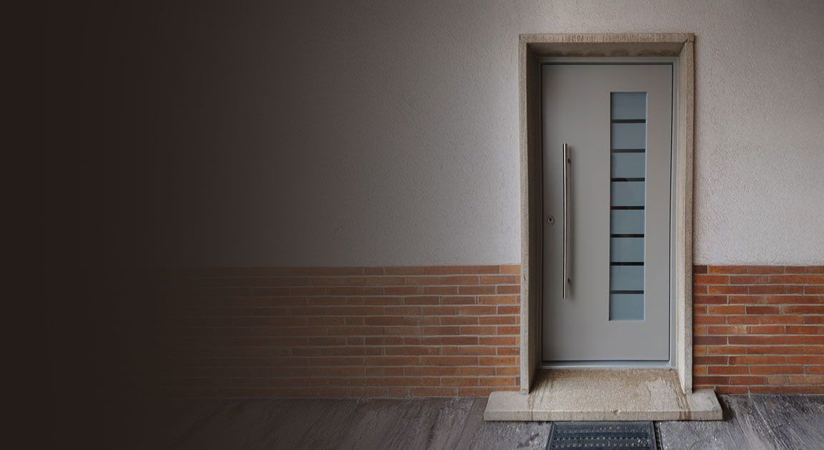Moderne graue Haustür mit langem Stangengriff und Glaseinsatz in einer Backsteinwand
